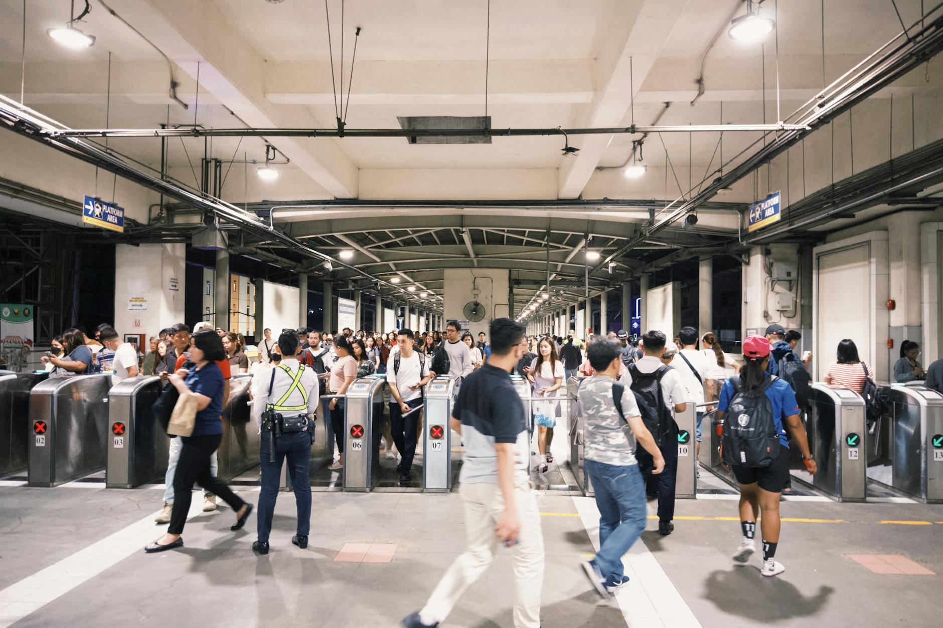 Tłum pasażerów przy bramkach w ruchliwej stacji metra