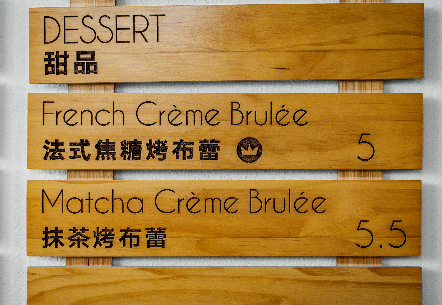 Drewniane menu deserów z crème brûlée opisane po angielsku i chińsku