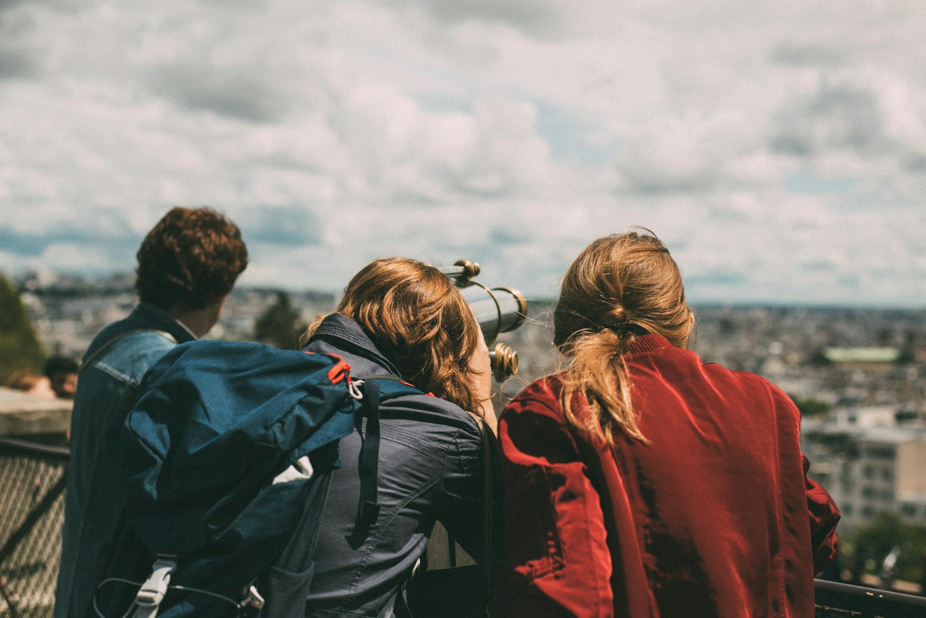 Młodzi turyści oglądają panoramę Paryża przez teleskop za dnia