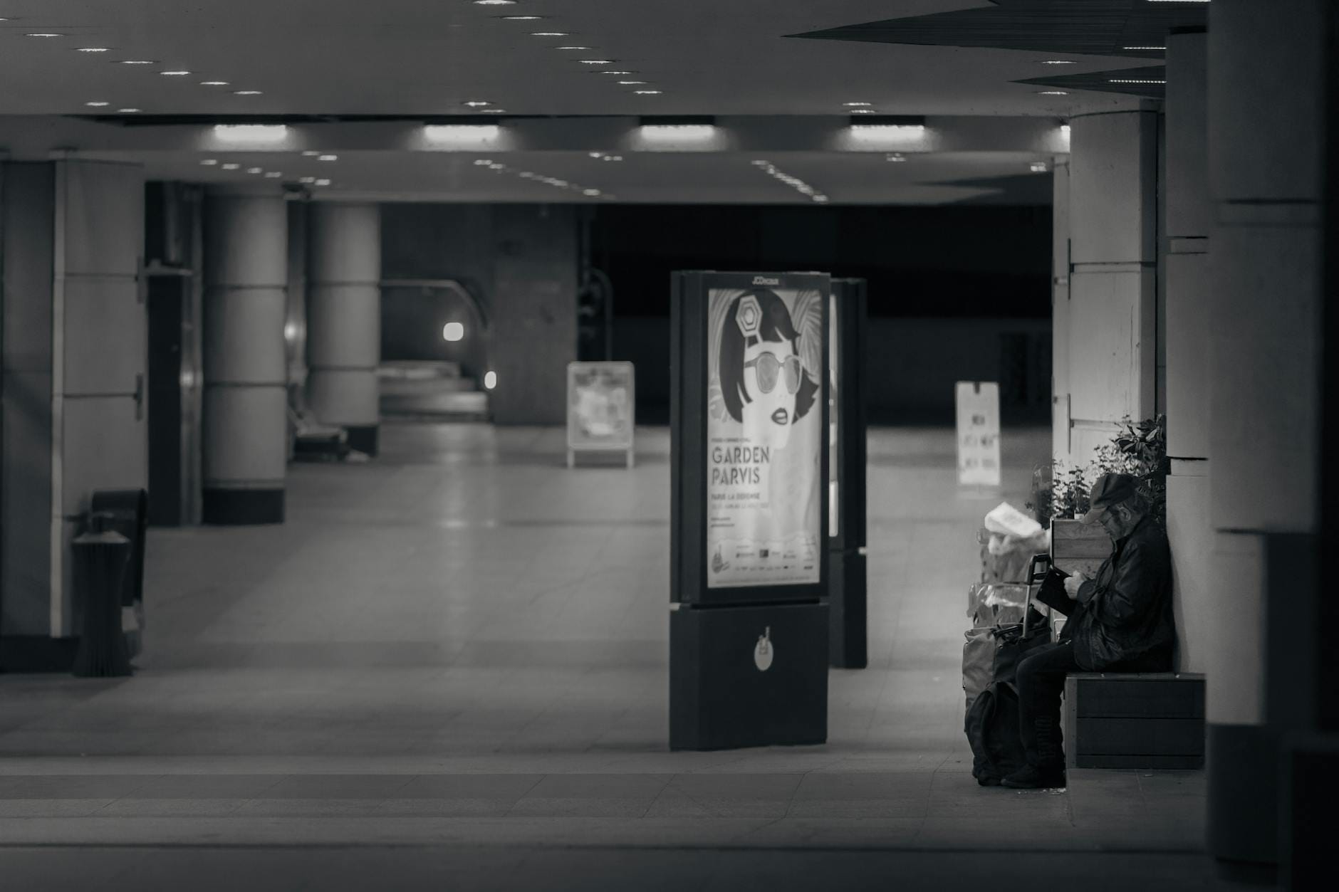 Osoba czytająca w czarno-białym korytarzu paryskiego metra