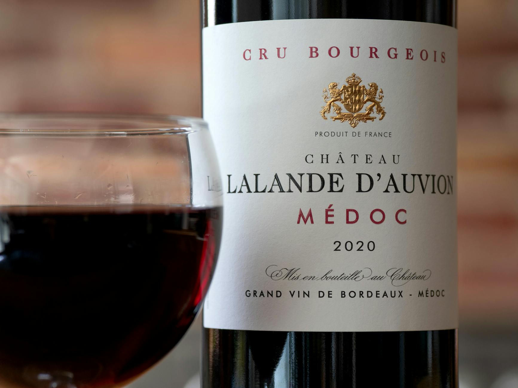 Butelka czerwonego wina Château Lalande D’Auvion Médoc 2020 i kieliszek