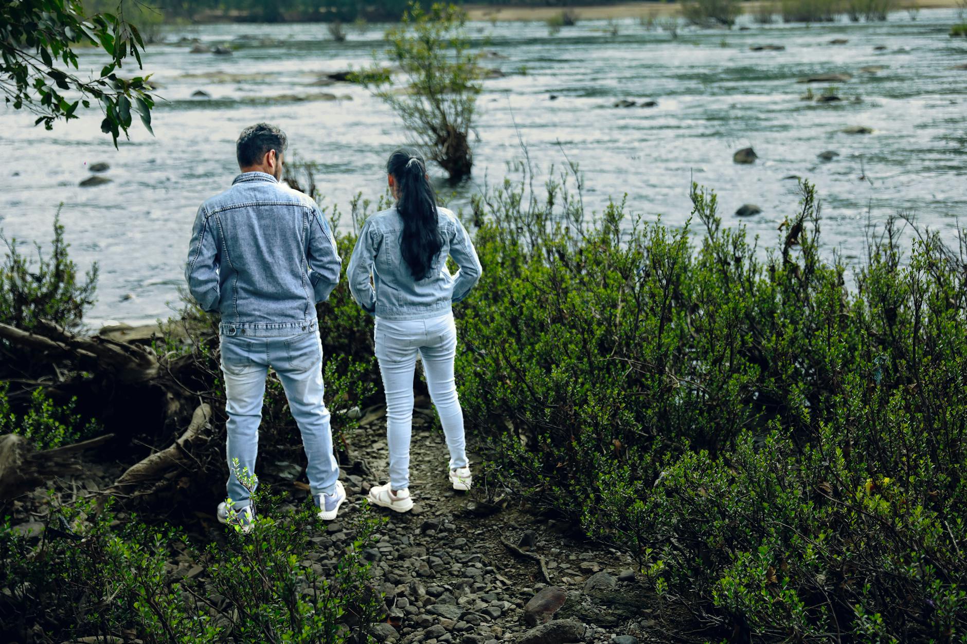 Para w dżinsowych kurtkach nad zielonym brzegiem Sekwany