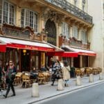 Jak działa napiwek we Francji: ile zostawić i kiedy wcale nie trzeba? Paryska restauracja z ogródkiem na ulicy pełnej przechodniów