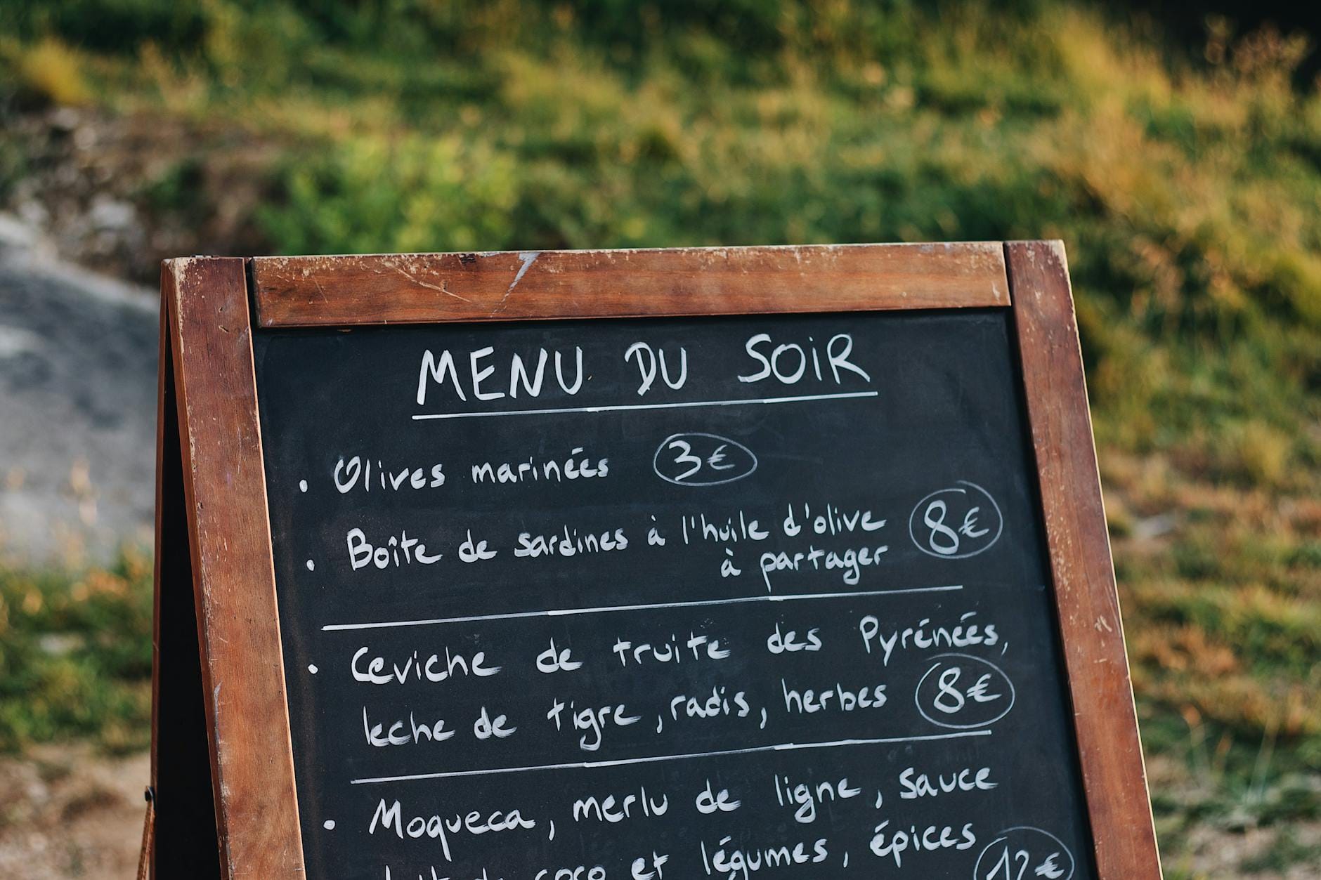 Tablica z kredowym menu po francusku przed restauracją na zewnątrz