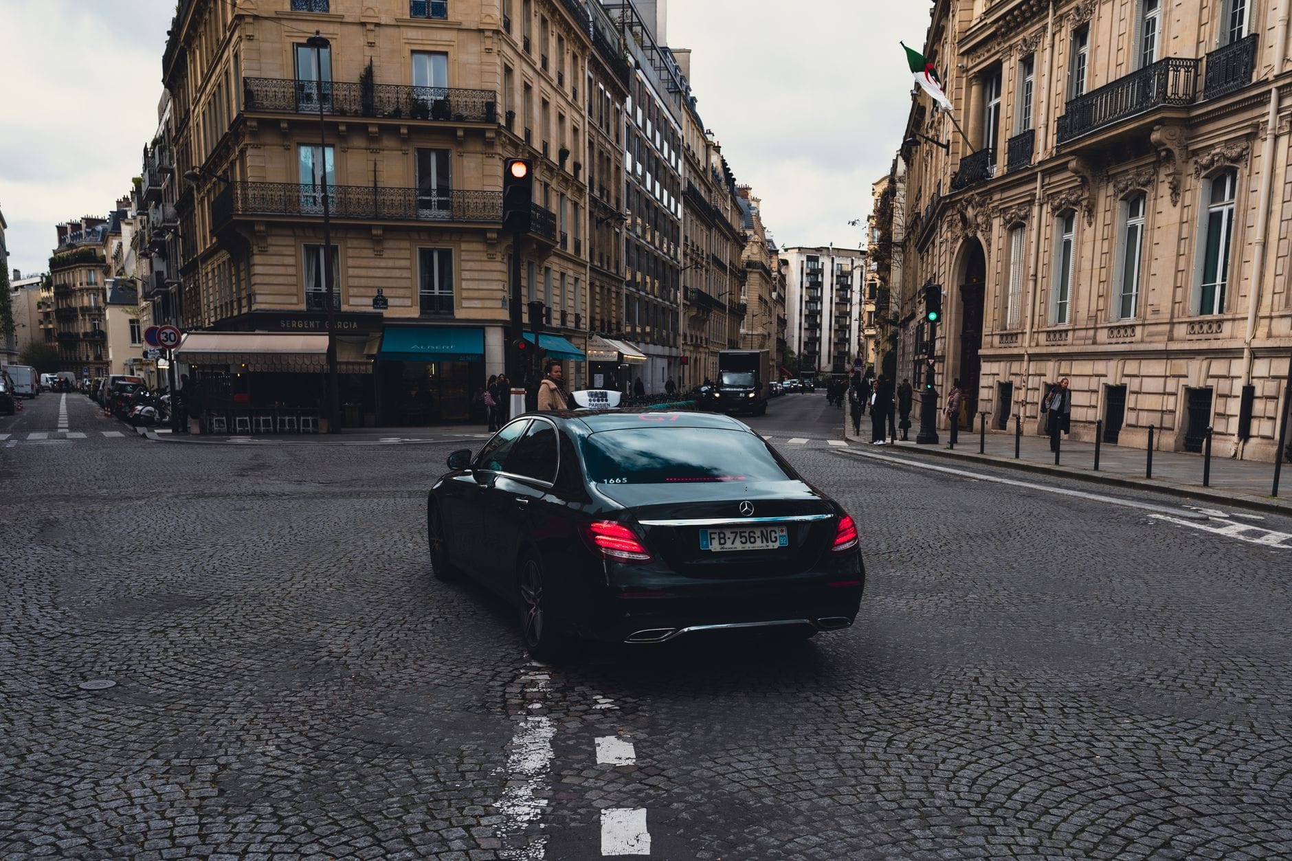Jak zamówić taxi lub VTC we Francji: podstawowe zasady i zwroty na trasę Czarna taksówka Mercedes jedzie ulicą w centrum Paryża