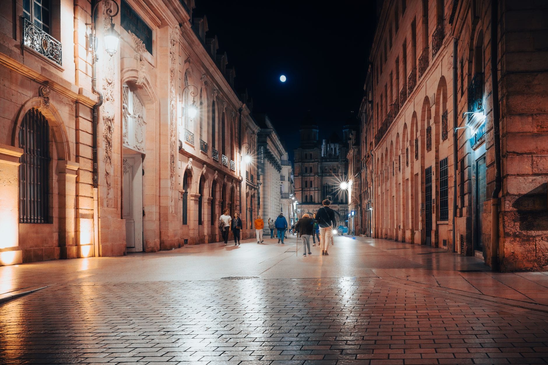 Nocny Dijon z oświetloną zabytkową architekturą i ruchliwą ulicą